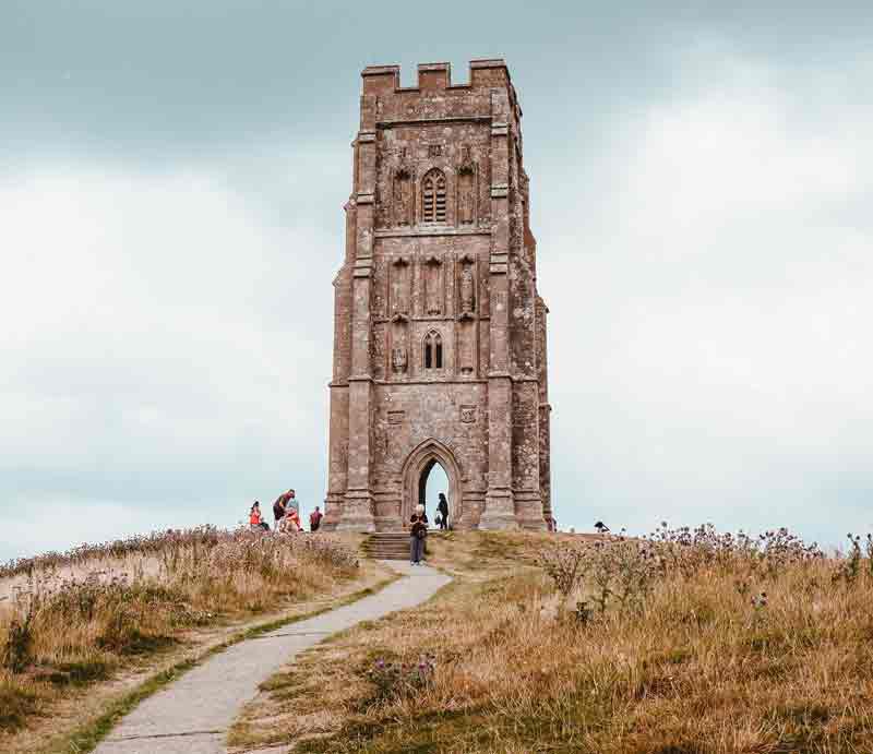 The tall stone-built St Michael's Tower atop the grassy hill.