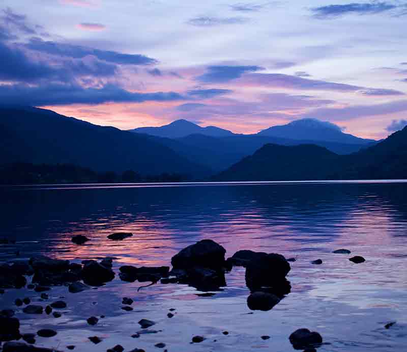 Atmospheric early evening with mountains and sky reflected in the water.