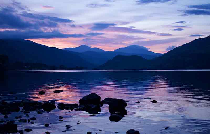 Atmospheric early evening with mountains and sky reflected in the water.